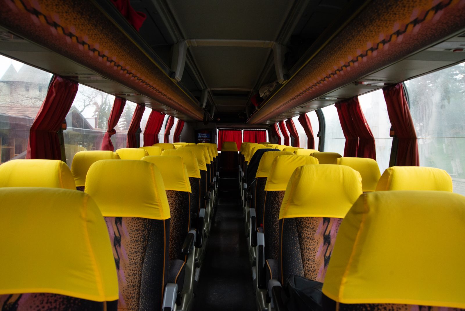 Aisle of an intercity coach with reclining seats and curtains